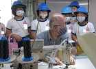 「ソーイング中村」さんの工場内で、大きなミシンで縫う様子を見せていただいています。