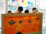 ４人の子どもが、作った作品を背景画の前で、動かしています。