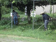 保護者の方が草刈り機で草を刈っています