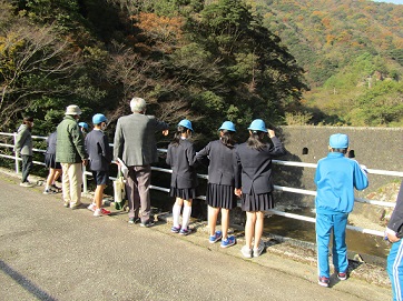 橋の上から川や山を眺めています。