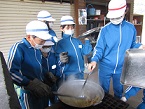 カレーうどんをかまどで調理中。おたまでかき混ぜています。